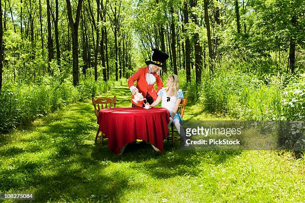 mad hatter serving alice tea at party - mad hatter stock pictures, royalty-free photos & images