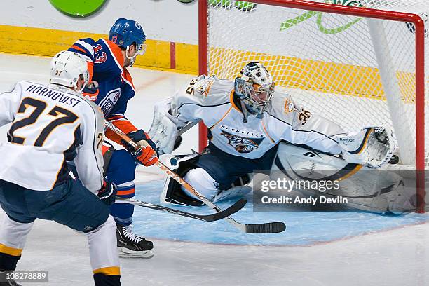 Andrew Cogliano of the Edmonton Oilers tips the puck past Pekka Rinne of the Nashville Predators at Rexall Place on January 23, 2011 in Edmonton,...