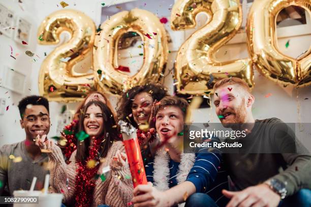 lachende tieners afvuren confetti - new year 2020 stockfoto's en -beelden