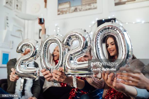 vrienden houden nieuwjaar ballonnen - new year 2020 stockfoto's en -beelden