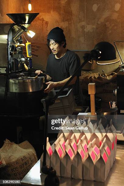 Kiduk Reus oversees espresso coffee beans roasting in his refurbished 1918 Probat coffee bean roaster next to bags of finished beans for sale at...