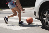 Young girl catching a basket ball on a pedestrian crossing