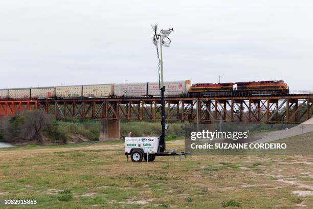 Border patrol floodlights are placed near the Rio Grande in Laredo, Texas, on January 14, 2019 as a train crosses the Texas-Mexican Railway...