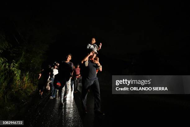 Man carries a child on his shoulders as Honduran migrants, part of the second caravan to the United States, leave San Pedro Sula, 180 km north of...