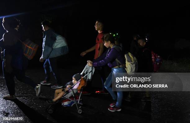 Woman pushes a baby in a stroller as Honduran migrants, part of the second caravan to the United States, leave San Pedro Sula, 180 km north of...