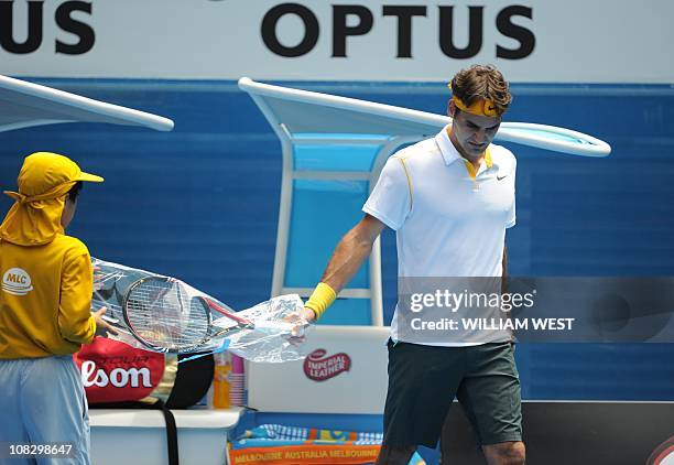 Roger Federer of Switzerland takes a fresh racquet during his quarter-final men's singles match against Stanislas Wawrinka of Switzerland on the...