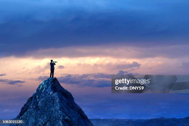 businessman standing looking through spyglass on mountain peak - acaso imagens e fotografias de stock