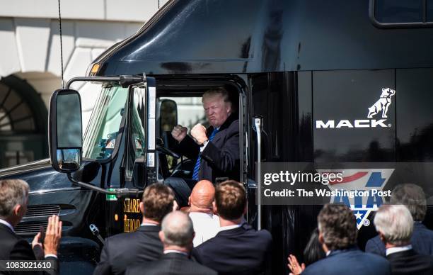 President Donald Trump jumps up in the cab of an 18 wheeler truck while meeting with truckers and CEOs regarding healthcare on the South Lawn of the...