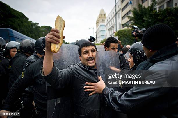 Tunisian protester holding bread is pushed by riot policemen during a demonstration in Tunis on January 18, 2011. Riot police fired tear gas and...