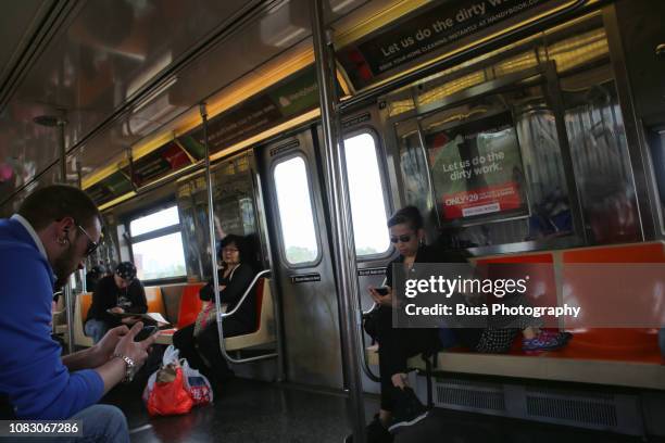 passengers checking their phones in the new york city subway. new york city, usa - chinese american railroad stock-fotos und bilder