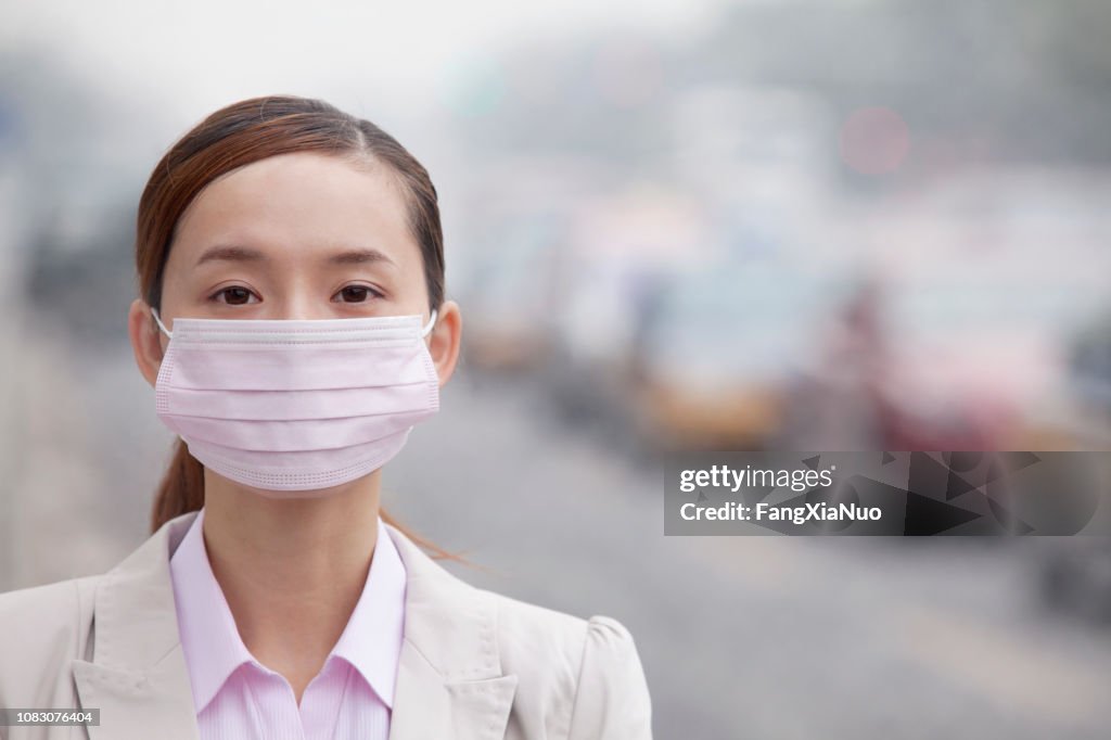 Mujer China con mascarilla debido a la contaminación del aire en la ciudad