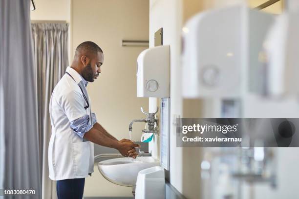 joven médico masculino, lavarse las manos en el fregadero - hand washing fotografías e imágenes de stock