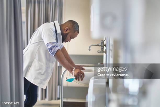 tensed doctor leaning over sink in hospital - tired healthcare worker stock pictures, royalty-free photos & images
