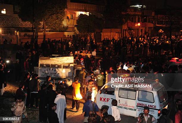 Pakistani security officials and local residents gather around wreckage of a police van after a motorcycle bomb blast in Karachi on January 25, 2011....