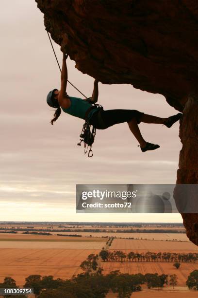 woman rockclimbing silhouette - overhangende rots stockfoto's en -beelden
