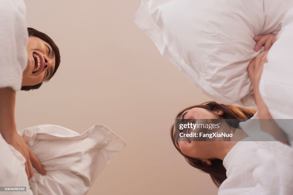 Chinese couple having pillow fight in bedroom