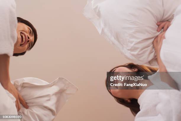 chinese couple having pillow fight in bedroom - pillow fight stock pictures, royalty-free photos & images