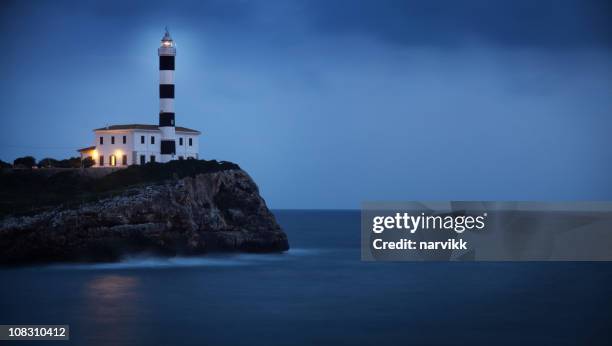 lighthouse on the cliff by blue twilight - lighthouse mallorca stock pictures, royalty-free photos & images