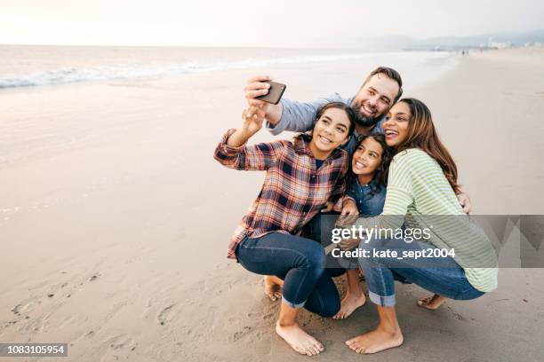 zwei eltern und zwei kinder, die am strand - hispanic man on beach stock-fotos und bilder