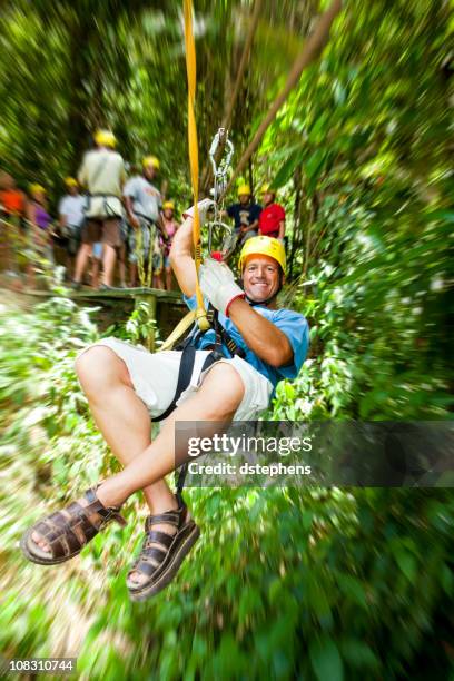 excited man in-motion on zipline in tropical jungle rainforest - roatan stock pictures, royalty-free photos & images