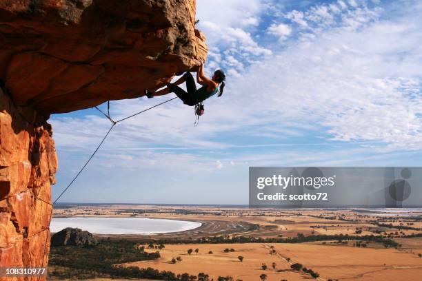 young woman rock climbing in the desert - overhangende rots stockfoto's en -beelden