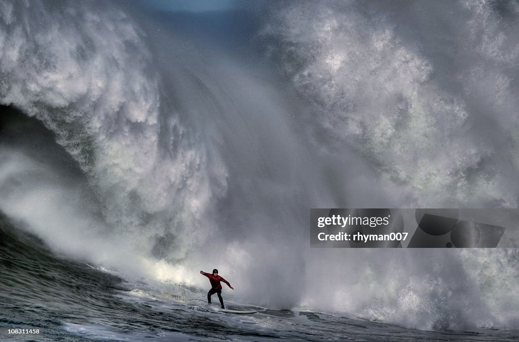 Surfer at the bottom of a huge crashing wave 