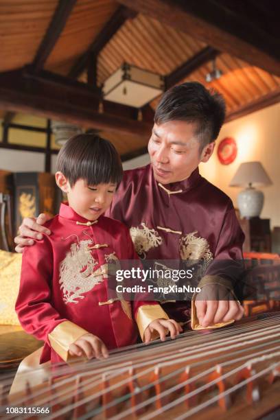 chinese vader en zoon in traditionele kleding speelt harp - jonglieren stockfoto's en -beelden