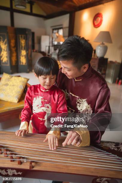 chinese vader en zoon in traditionele kleding speelt harp - jonglieren stockfoto's en -beelden