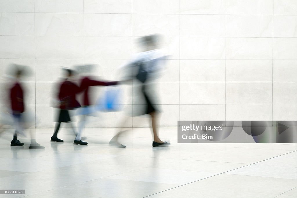 School children walking with female teacher, motion blur