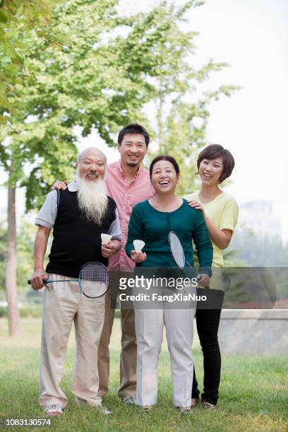 famiglia cinese sorridente nel parco - playing badminton foto e immagini stock