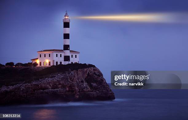 fulgido faro sulla scogliera di notte - faro foto e immagini stock