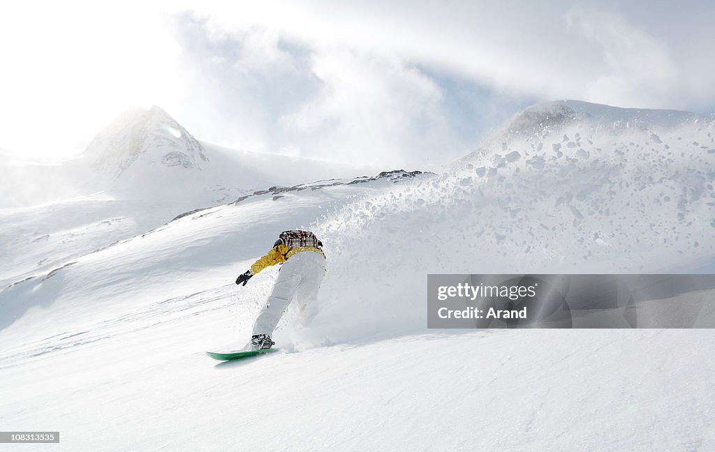 Person Snowboarding Down Mountain on Cloudy Day