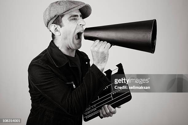 film director shouting with megaphone while holding film slate - film director stock pictures, royalty-free photos & images