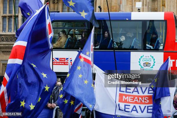 Passengers on a sightseeing tour bus pass anti and pro-Brexit demonstrators waving European Union , British Union flags, also known as Union Jacks,...