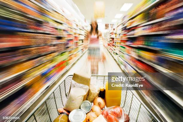 shopping cart races through store with rainbow motion blur surrounding - rush shopping stock pictures, royalty-free photos & images