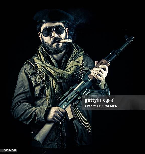 soldier smoking cigar and holding a gun - kalasjnikov stockfoto's en -beelden