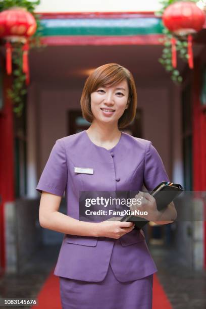 chinese receptionist standing in hotel - chinese waiter stock pictures, royalty-free photos & images