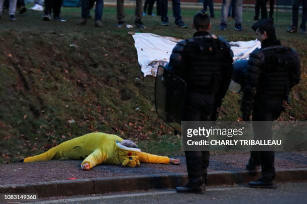 Yellow Vest" protester dressed as Pikachu from Pokemon lies on the roadside next to two French gendarmes in a roundabout in Grand Bourgtheroulde,...