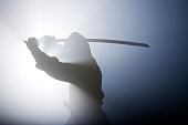Silhouette of ninja swinging sword in fog