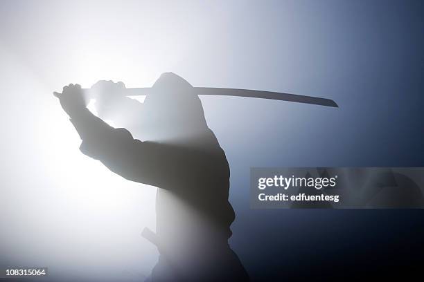 silhouette of ninja swinging sword in fog - ninja weapon stock pictures, royalty-free photos & images