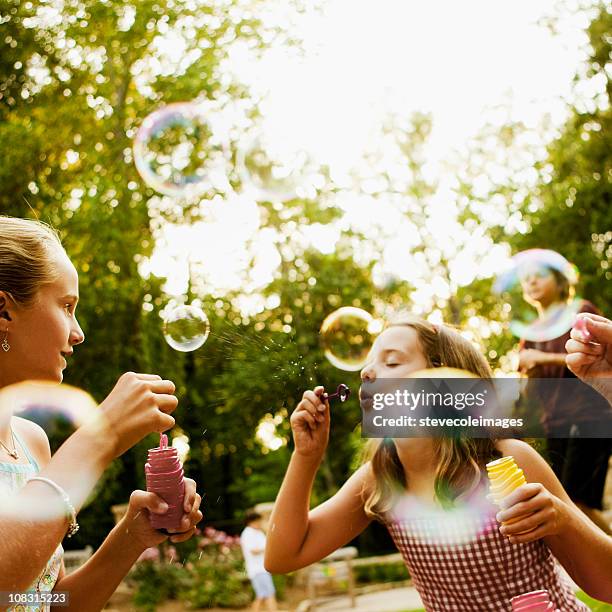 bambini soffiare le bollicine nel parco - bubble wand foto e immagini stock