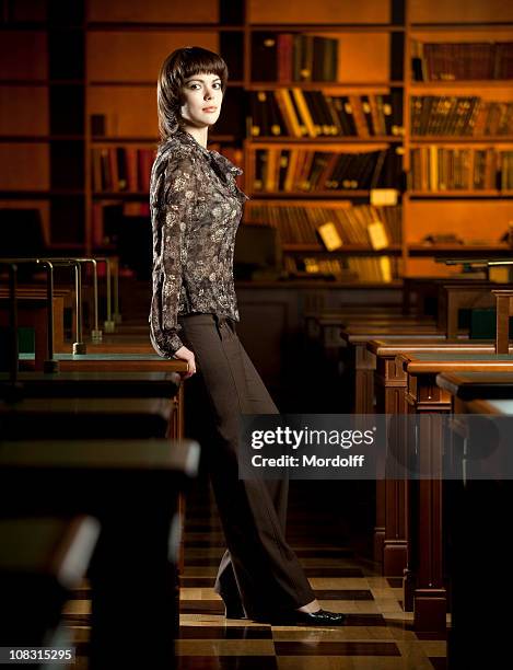 schöne junge frau stehend in der bibliothek - librarian stock-fotos und bilder