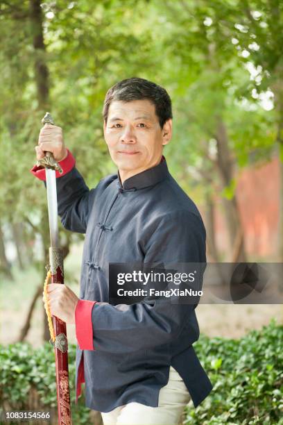 older chinese man practicing taiji in park - chinese martial arts stock pictures, royalty-free photos & images