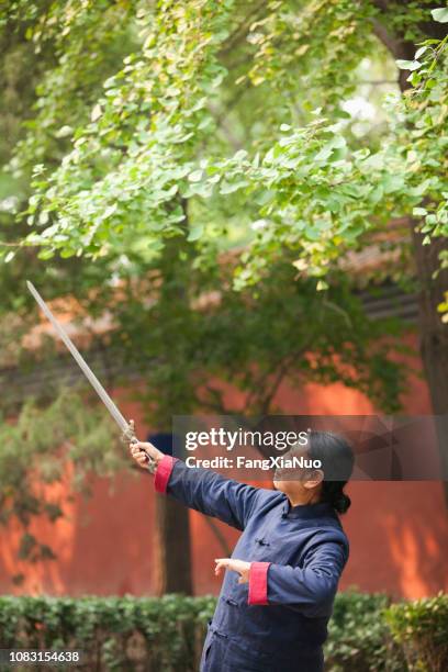older chinese woman practicing taiji in park - kung fu pose stock pictures, royalty-free photos & images