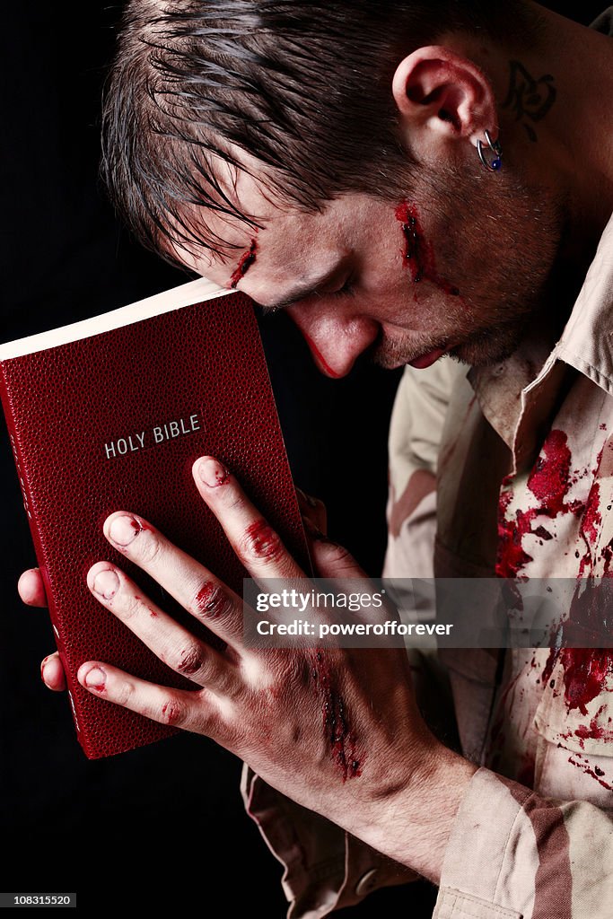 Verletzter Soldaten Holding Bibel zu fahren.
