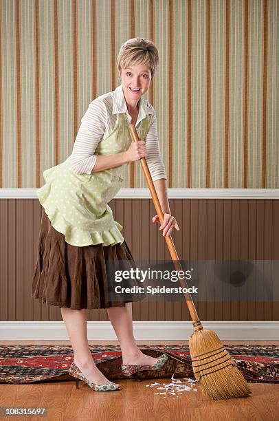 housewife sweeping dirt under the rug - vegen stockfoto's en -beelden