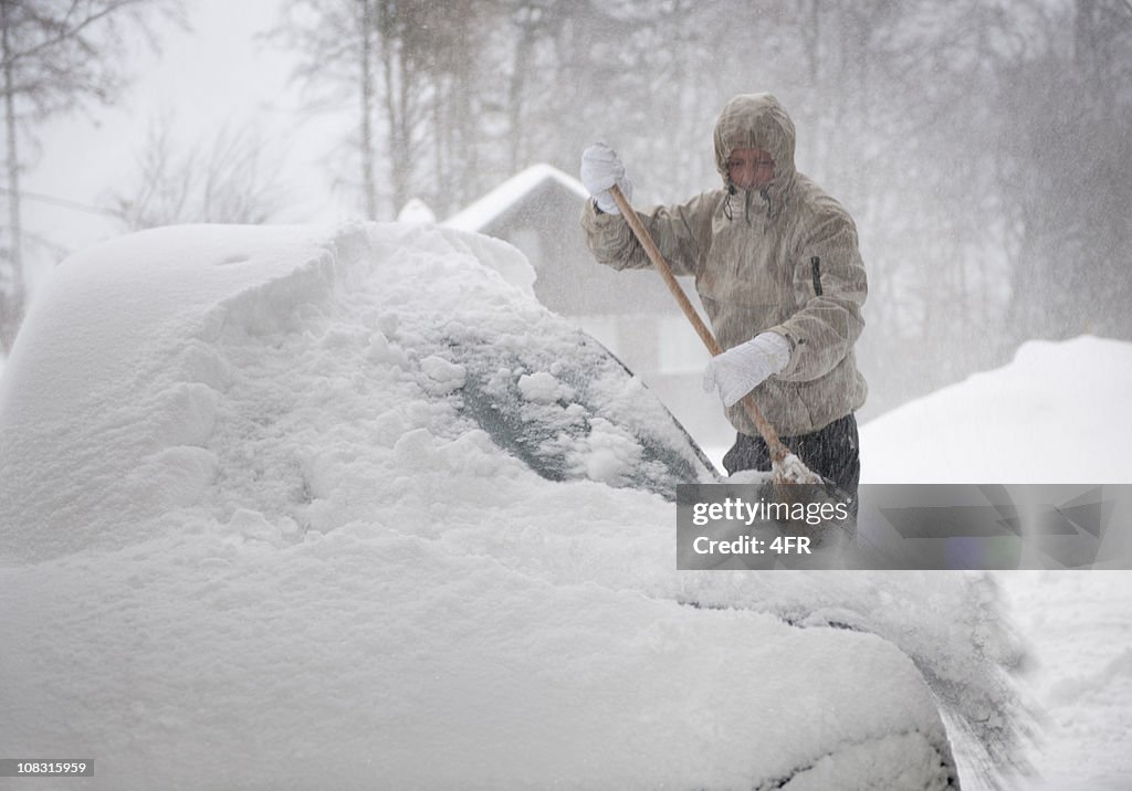 Man freeing car from snow in a blizzard (XXXL)