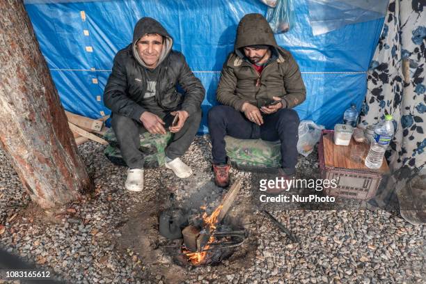 Two newcomers refugees out of their tent with snow around, living in makeshift tents, using fire to warm up, in Diavata Refugee camp, former...