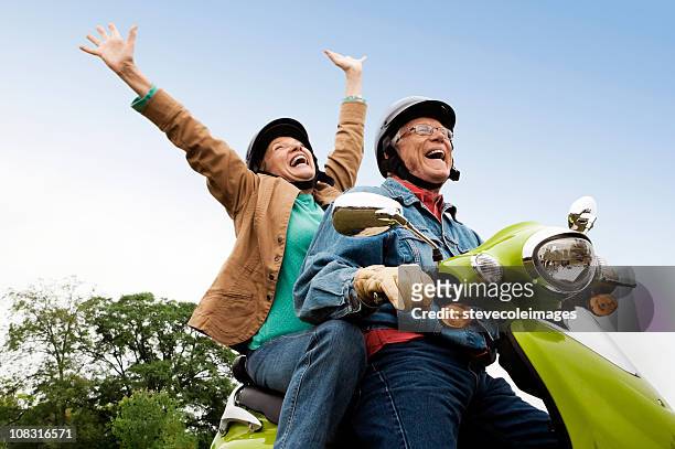 anziana coppia su scooter - anziani attivi foto e immagini stock