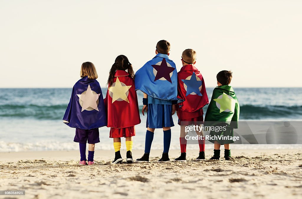 Fünf jungen Kindern angezogen wie Superhelden am Strand